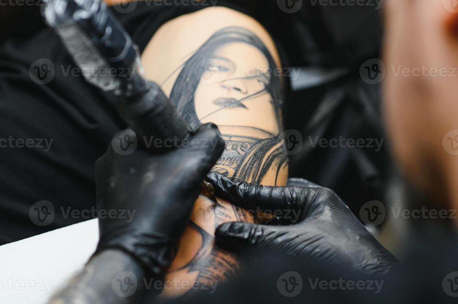 tattooist with his machine tattooing on the arm with the design drawn, concept of art and design photo