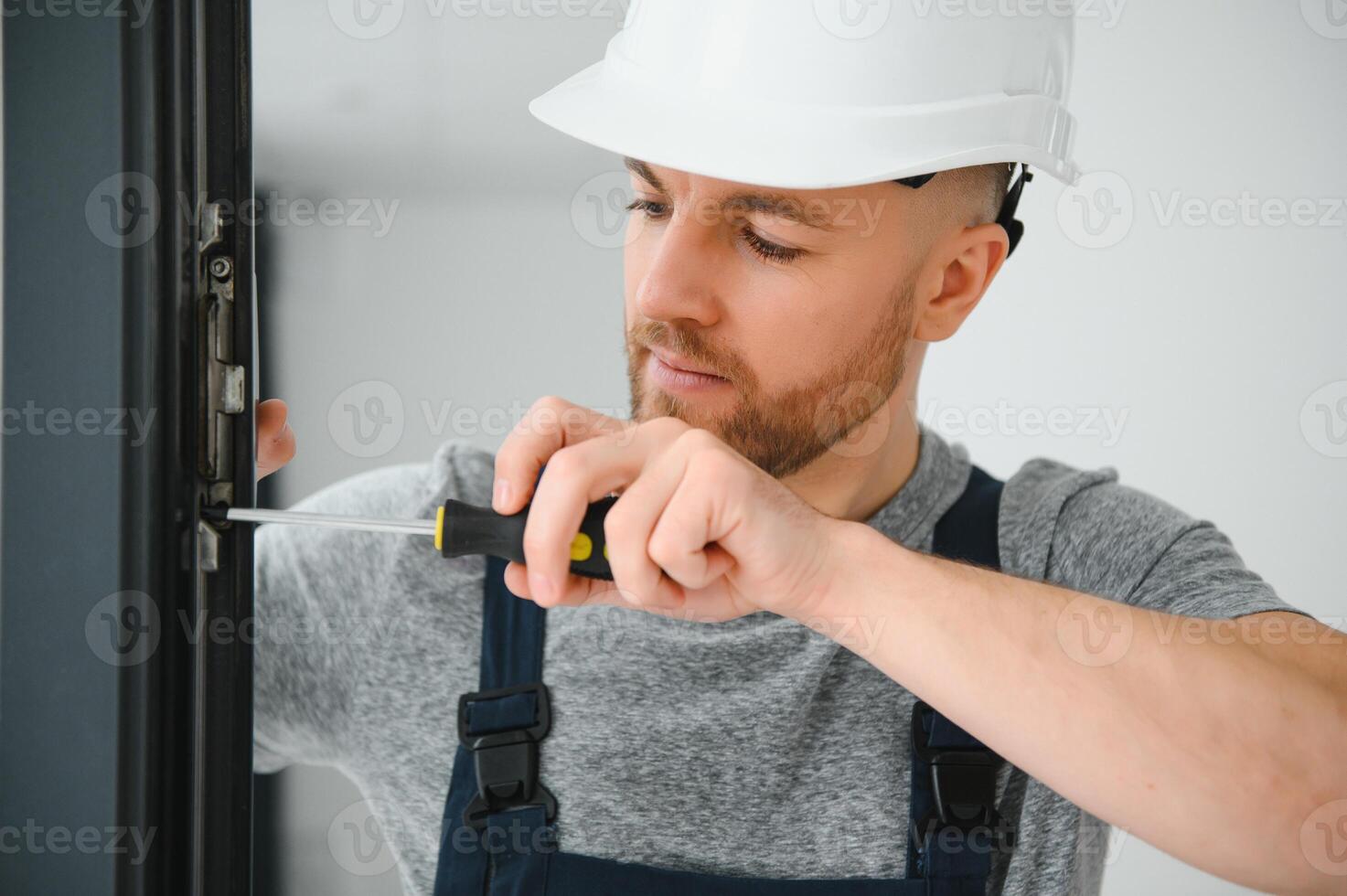 service man installing window with screwdriver photo