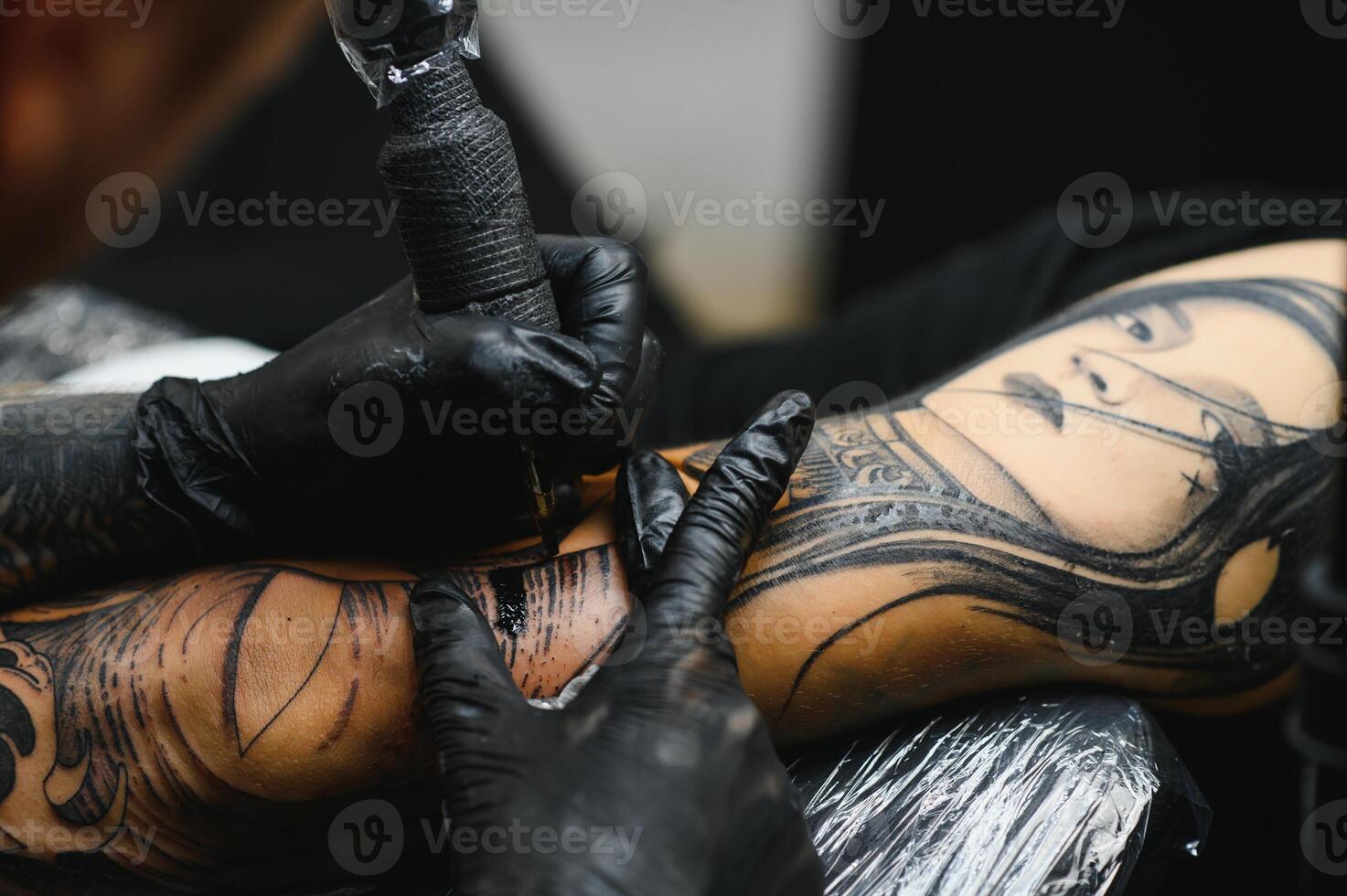 tattooist with his machine tattooing on the arm with the design drawn, concept of art and design photo