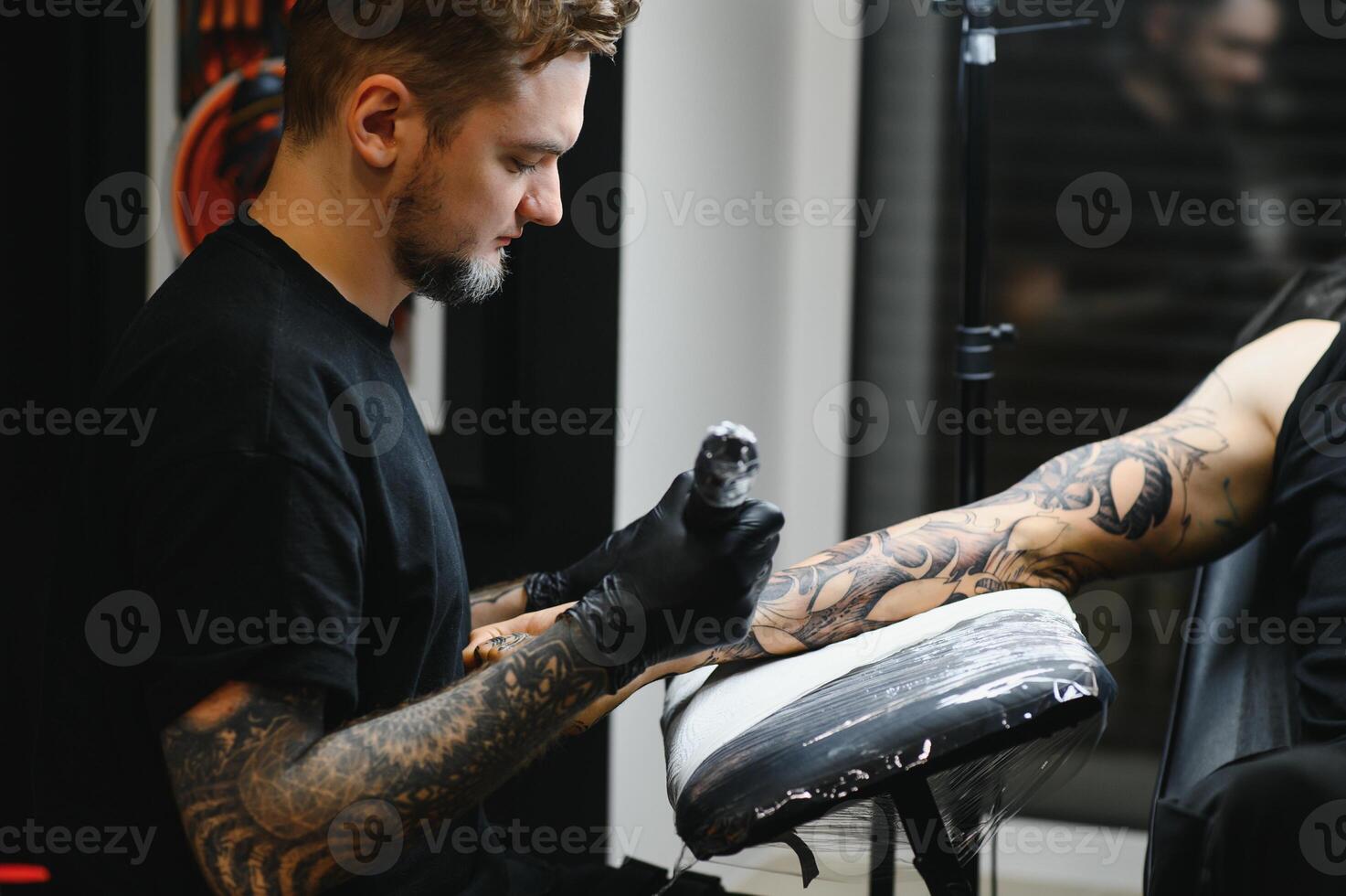 tattooist with his machine tattooing on the arm with the design drawn, concept of art and design photo