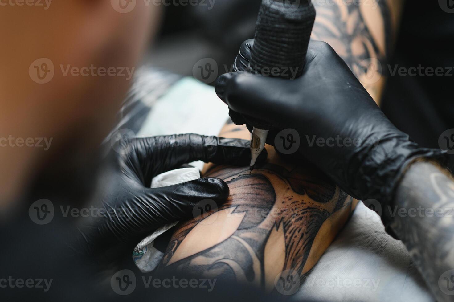 tattooist with his machine tattooing on the arm with the design drawn, concept of art and design photo
