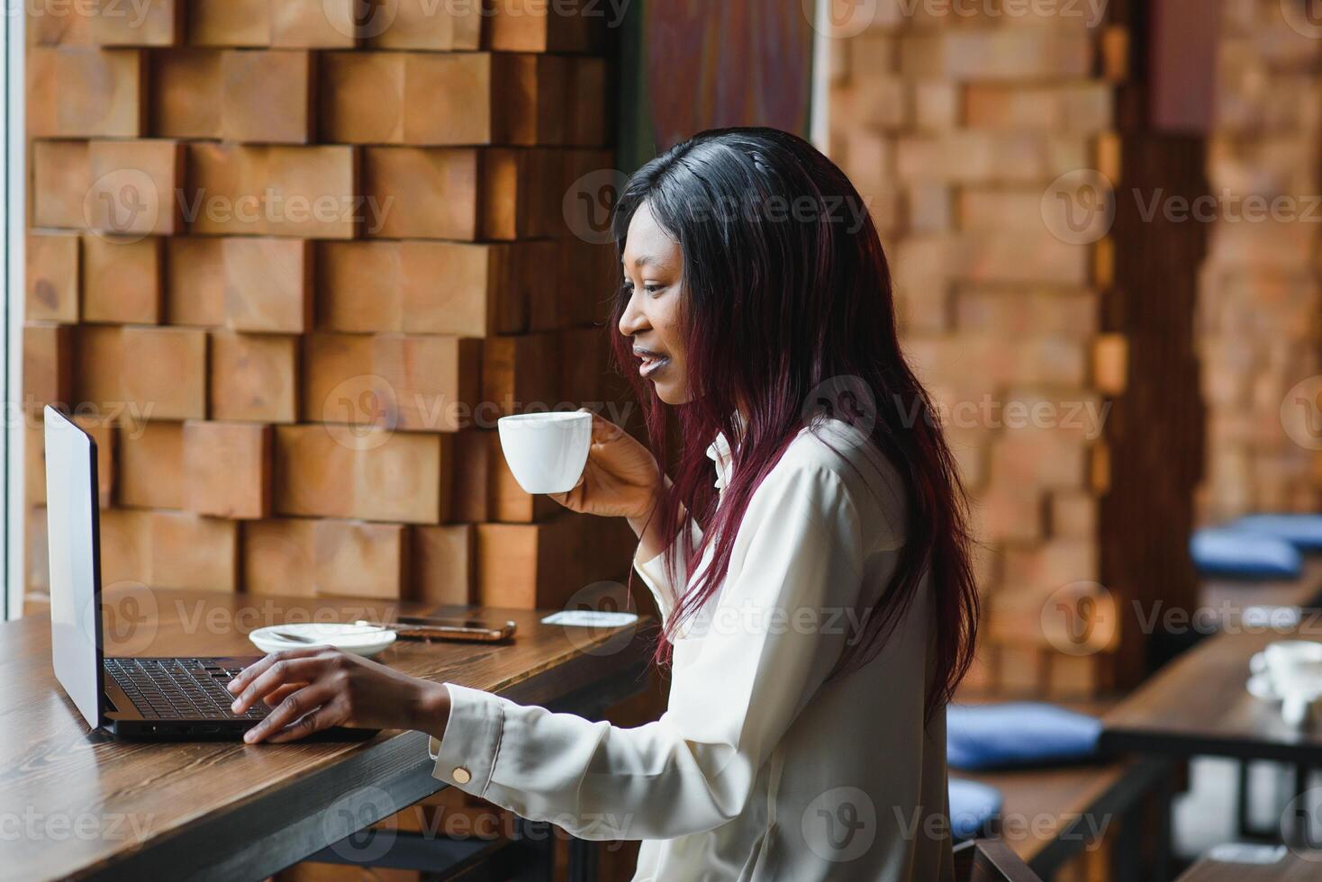 Young business woman is arranging the next business meeting in a modern coworking space by using a laptop. Young freelancer female is reading emails and other messages on a mobile phone. photo