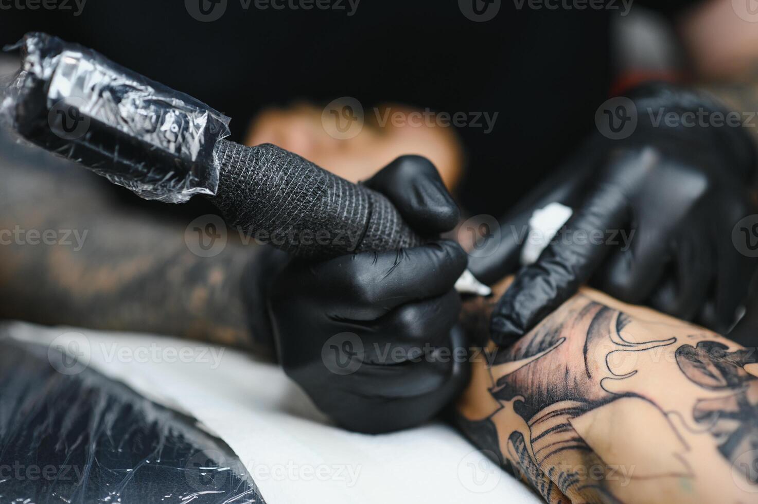 Tattoo salon. The tattoo master is tattooing a man. Tattoo machine, safety and hygiene at work. Close-up, tinted, tattooist. photo