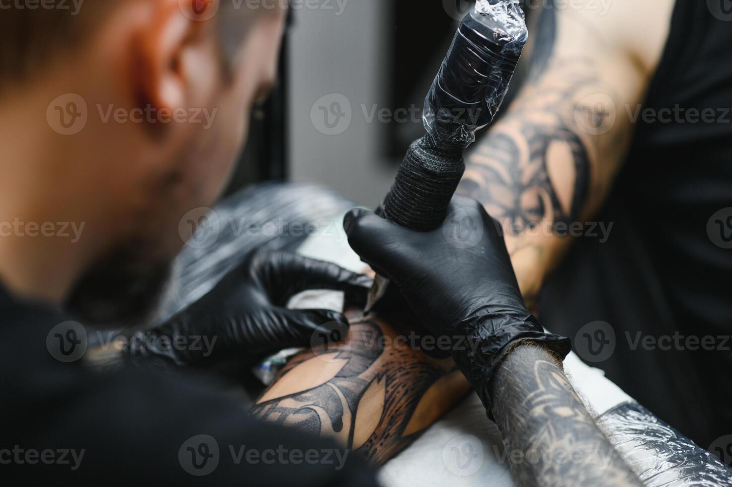 tattooist with his machine tattooing on the arm with the design drawn, concept of art and design photo