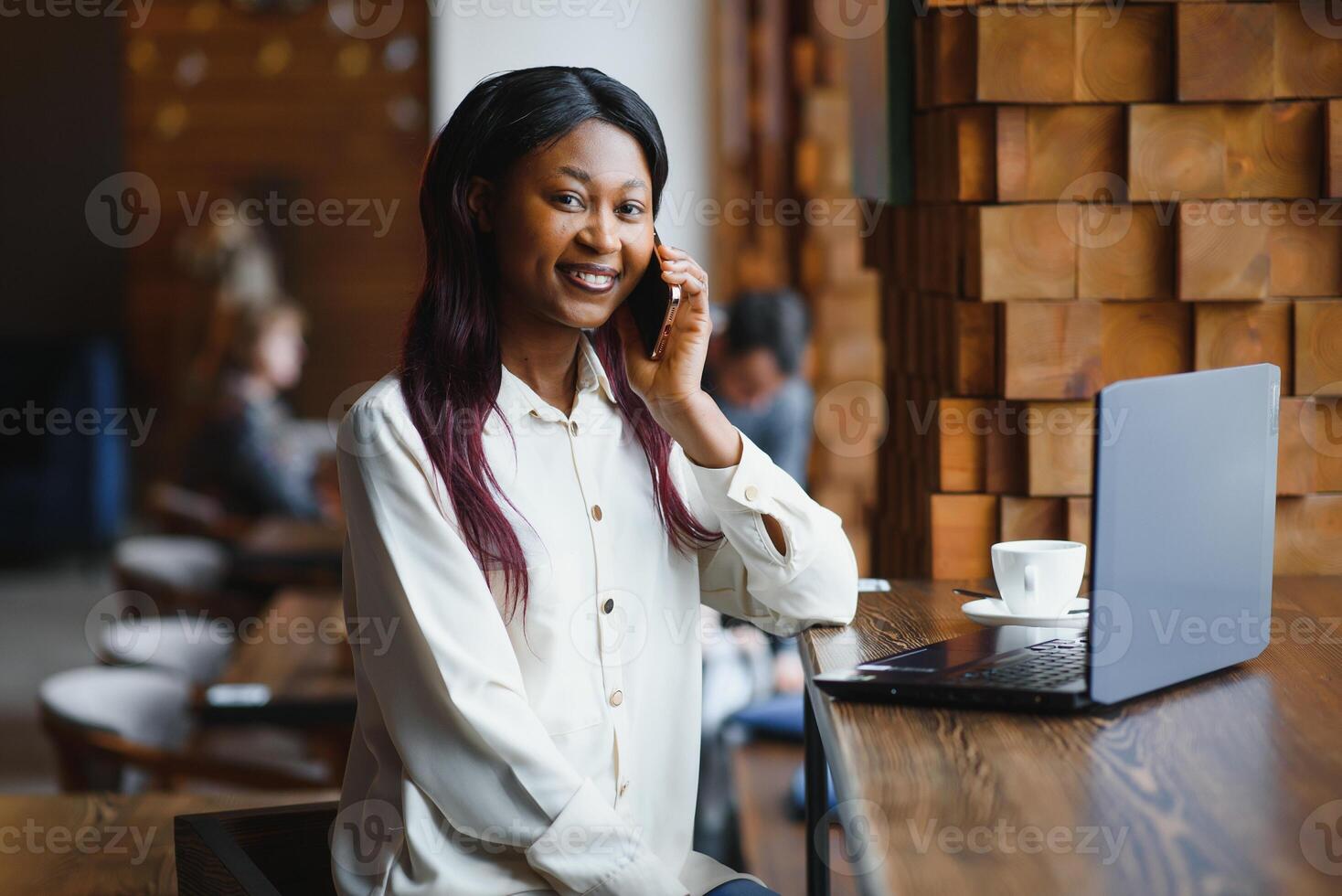 Young business woman is arranging the next business meeting in a modern coworking space by using a laptop. Young freelancer female is reading emails and other messages on a mobile phone. photo