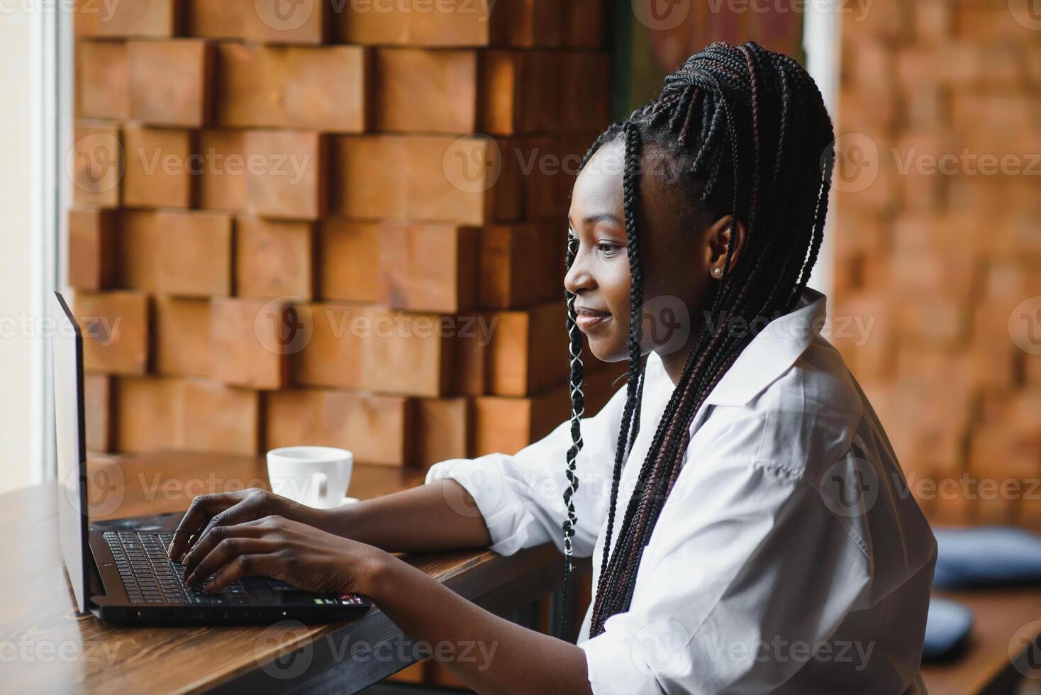 Happy african american woman worker using laptop work study at computer in loft office or cafe, smiling mixed race female student freelancer using pc app dating communicating online watching webinar photo