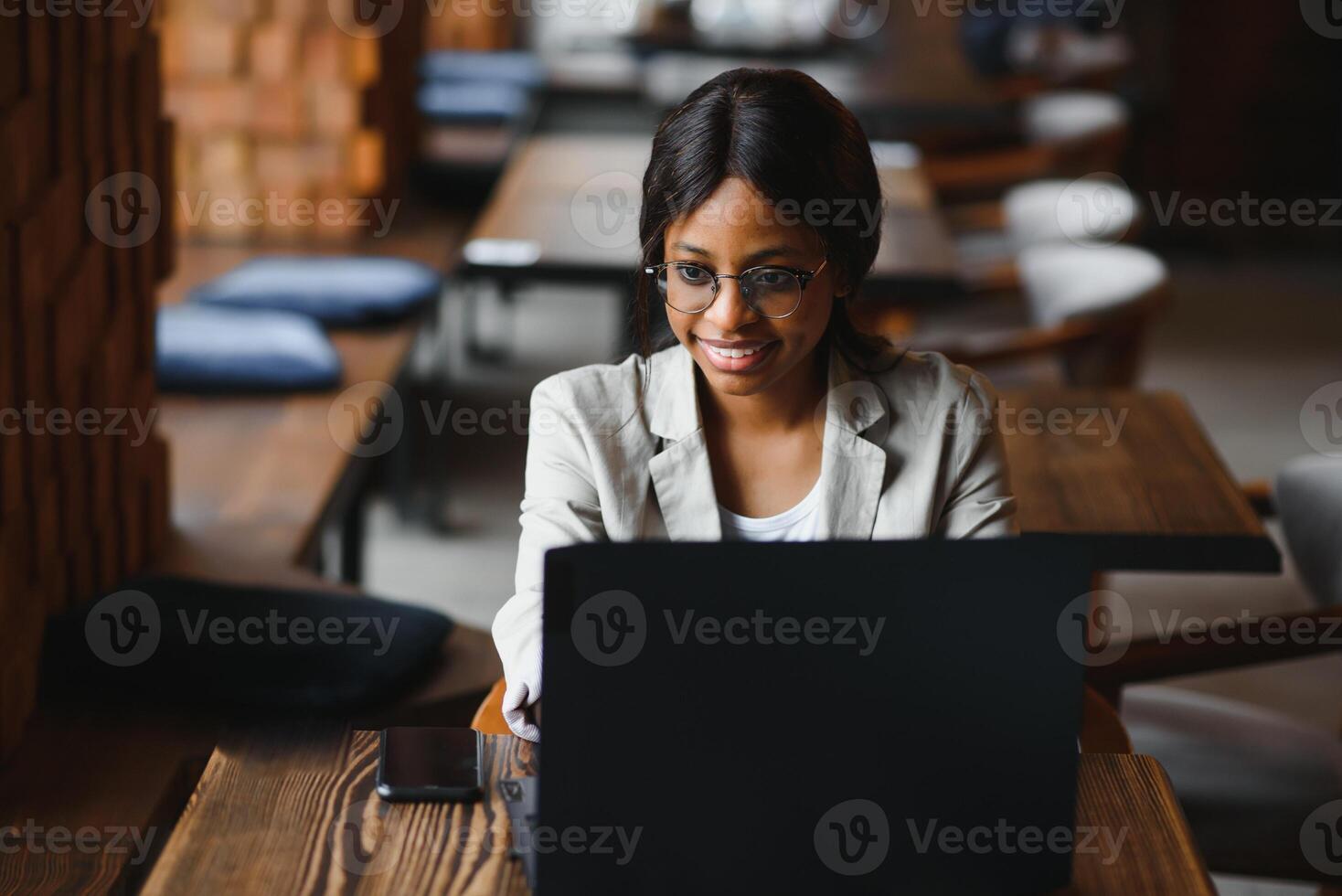 Happy african american woman worker using laptop work study at computer in loft office or cafe, smiling mixed race female student freelancer using pc app dating communicating online watching webinar photo
