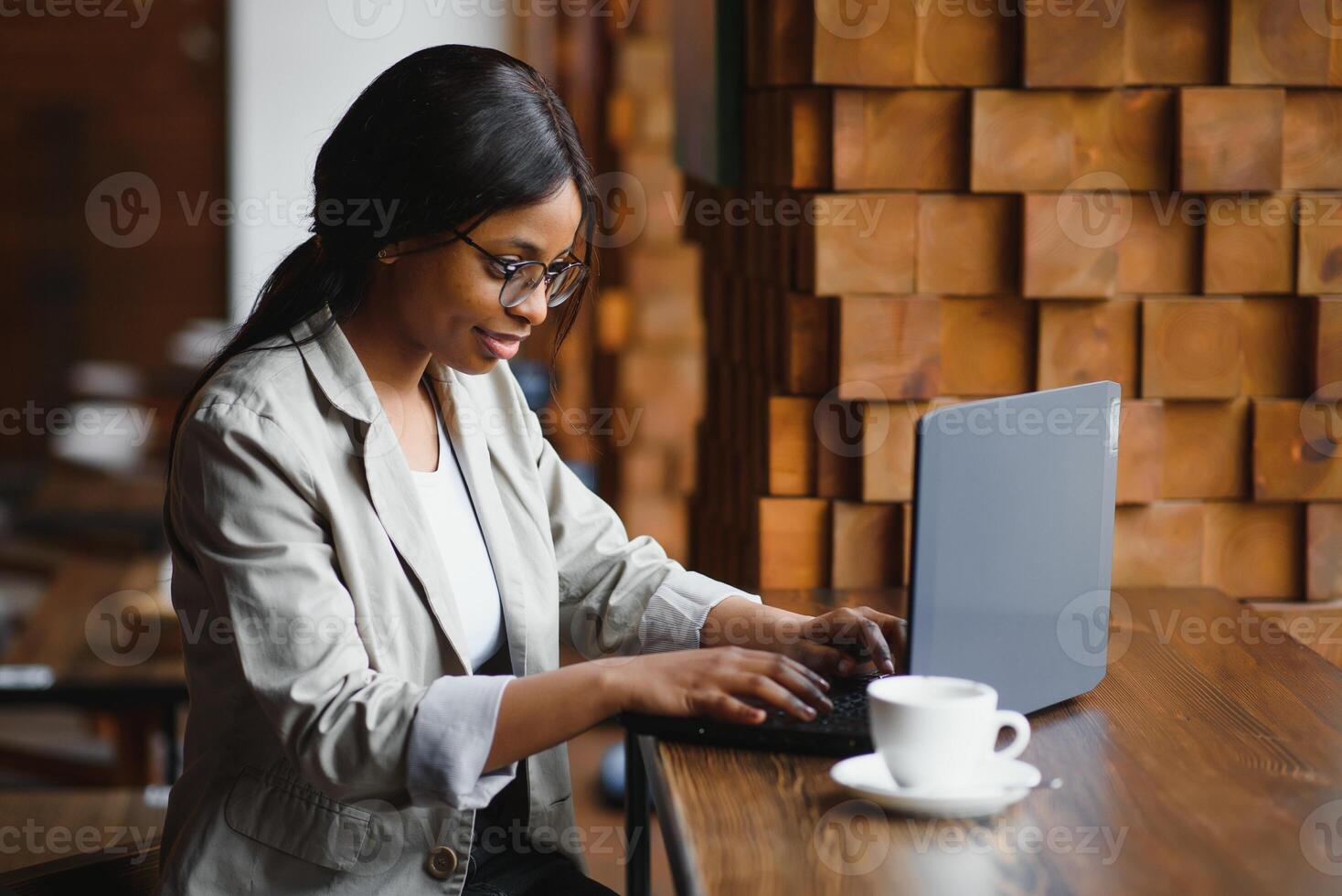 Happy african american woman worker using laptop work study at computer in loft office or cafe, smiling mixed race female student freelancer using pc app dating communicating online watching webinar photo