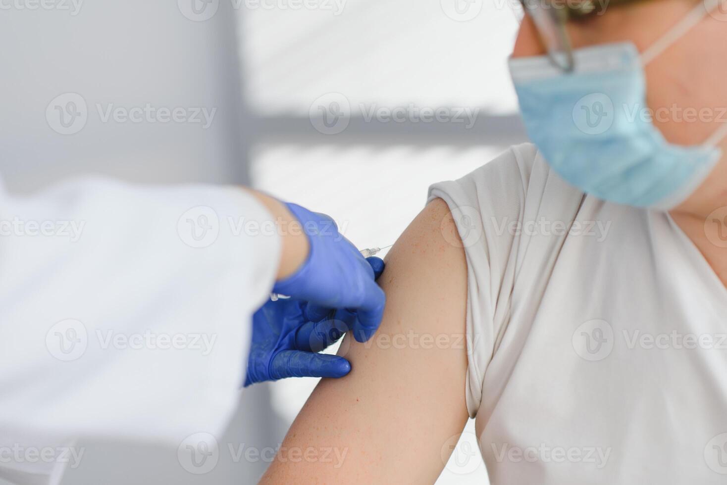 Close up of a Doctor making a vaccination in the shoulder of patient, Flu Vaccination Injection on Arm, coronavirus, covid-19 vaccine disease preparing for human clinical trials vaccination shot. photo