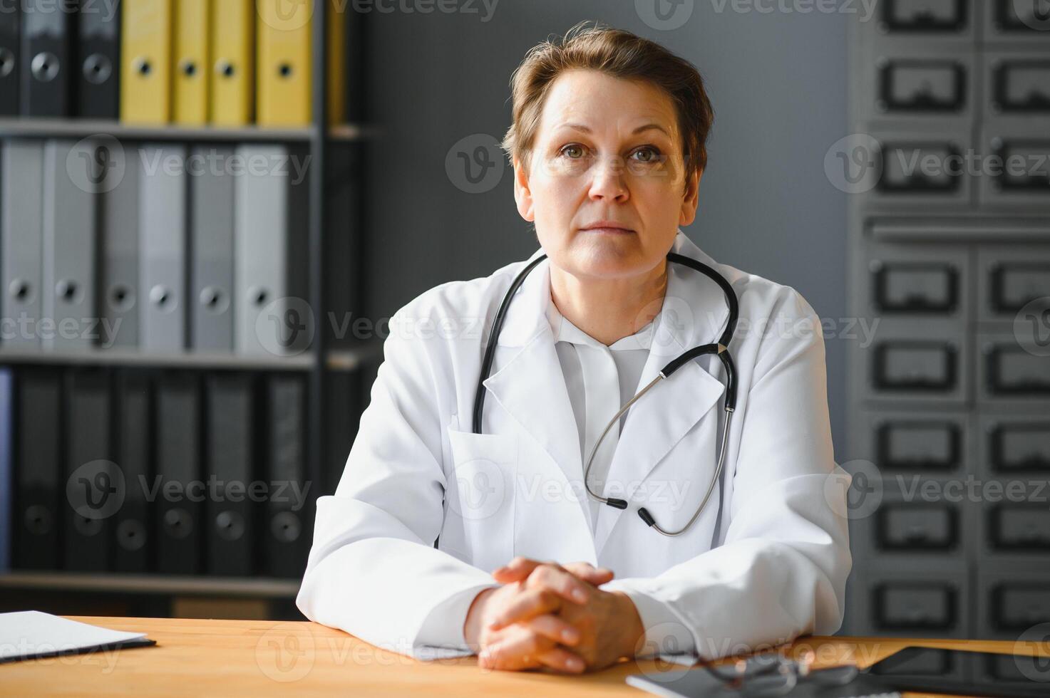 Portrait of mature female doctor in white coat at workplace photo