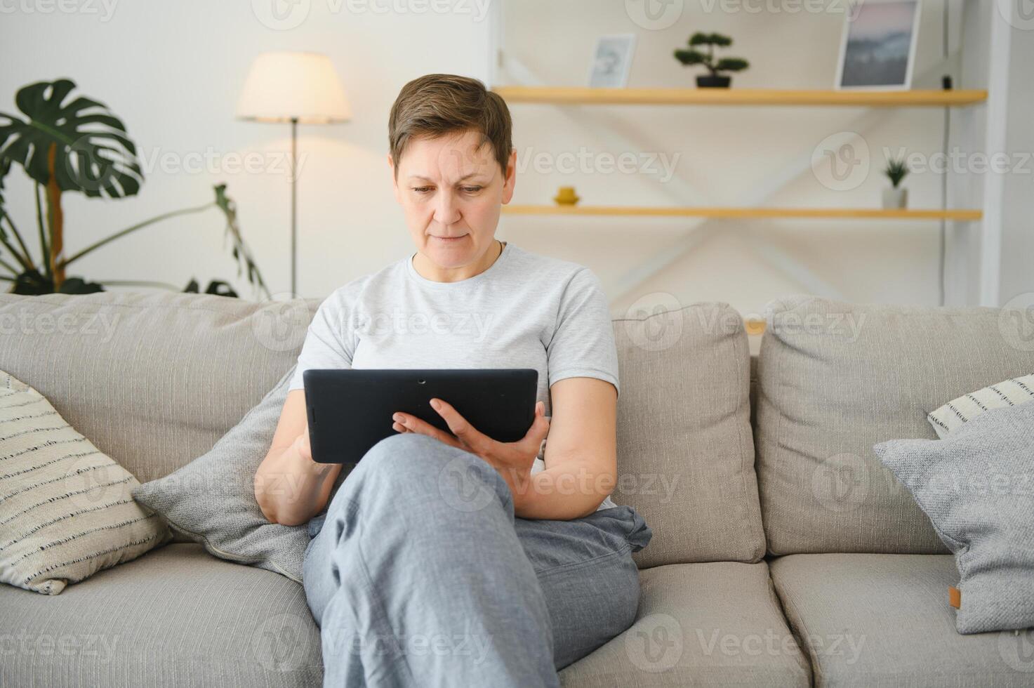 people, technology and internet concept - happy middle aged woman with tablet pc computer at home. photo