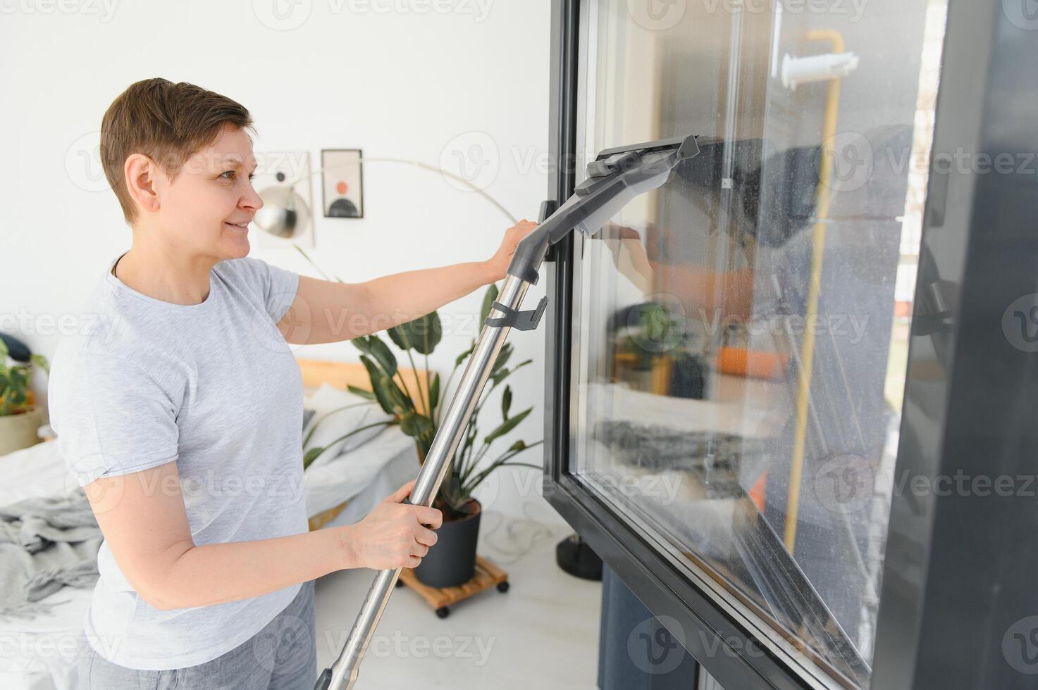 An attractive middle-aged woman is washing a window in a room photo