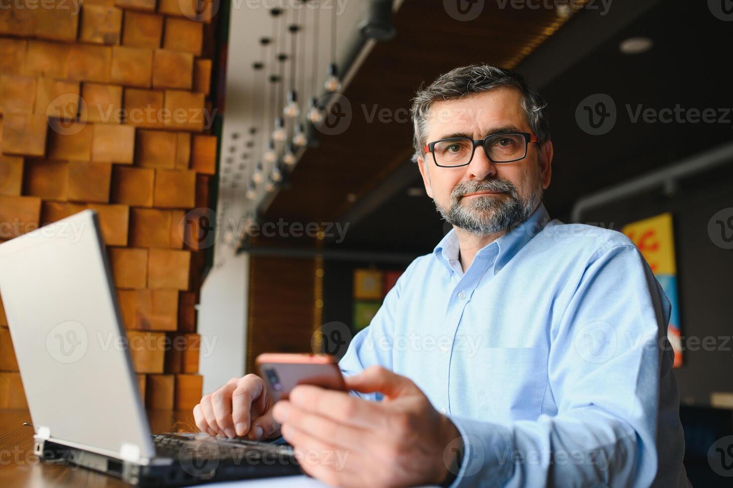 Male freelancer is working in a cafe on a new business project. Sits at a large window at the table. Looks at a laptop screen with a cup of coffee photo