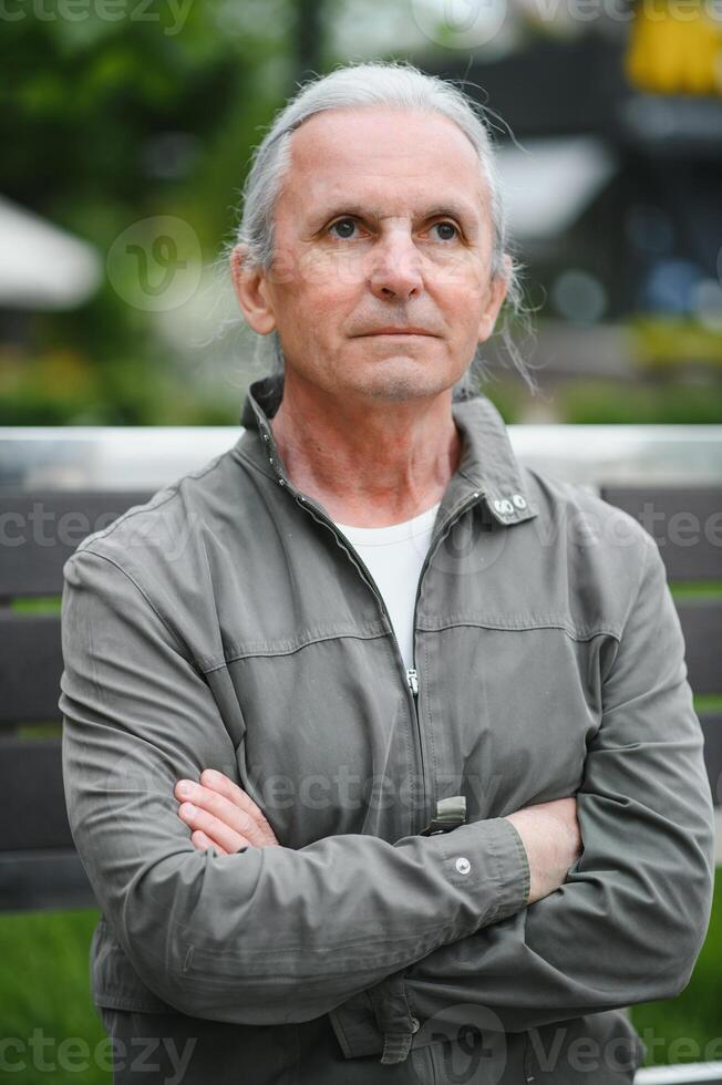 Old gray-haired man rest on the bench in summer park photo
