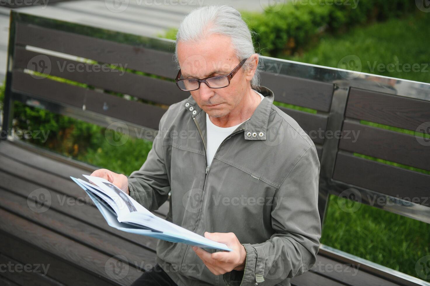 Old gray-haired man rest on the bench in summer park photo
