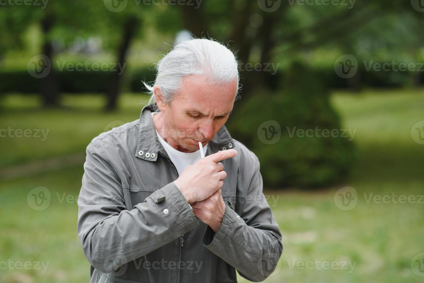 An old senior man smoking cigarette outside, smoke addiction, bad habbit photo
