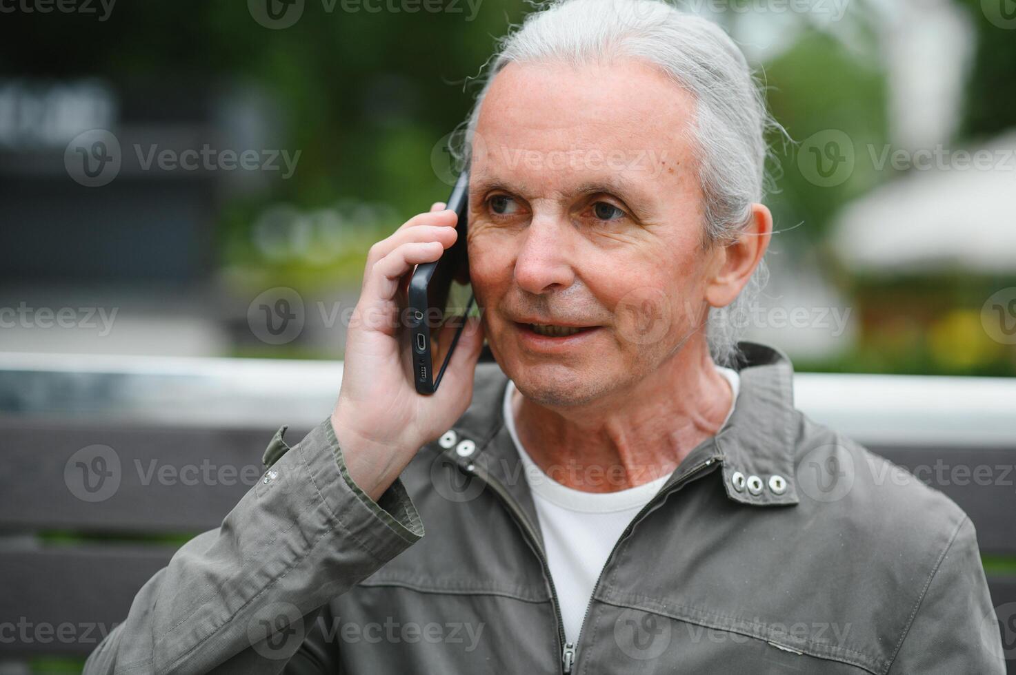 Old man browsing app on smartphone, outdoor in park photo
