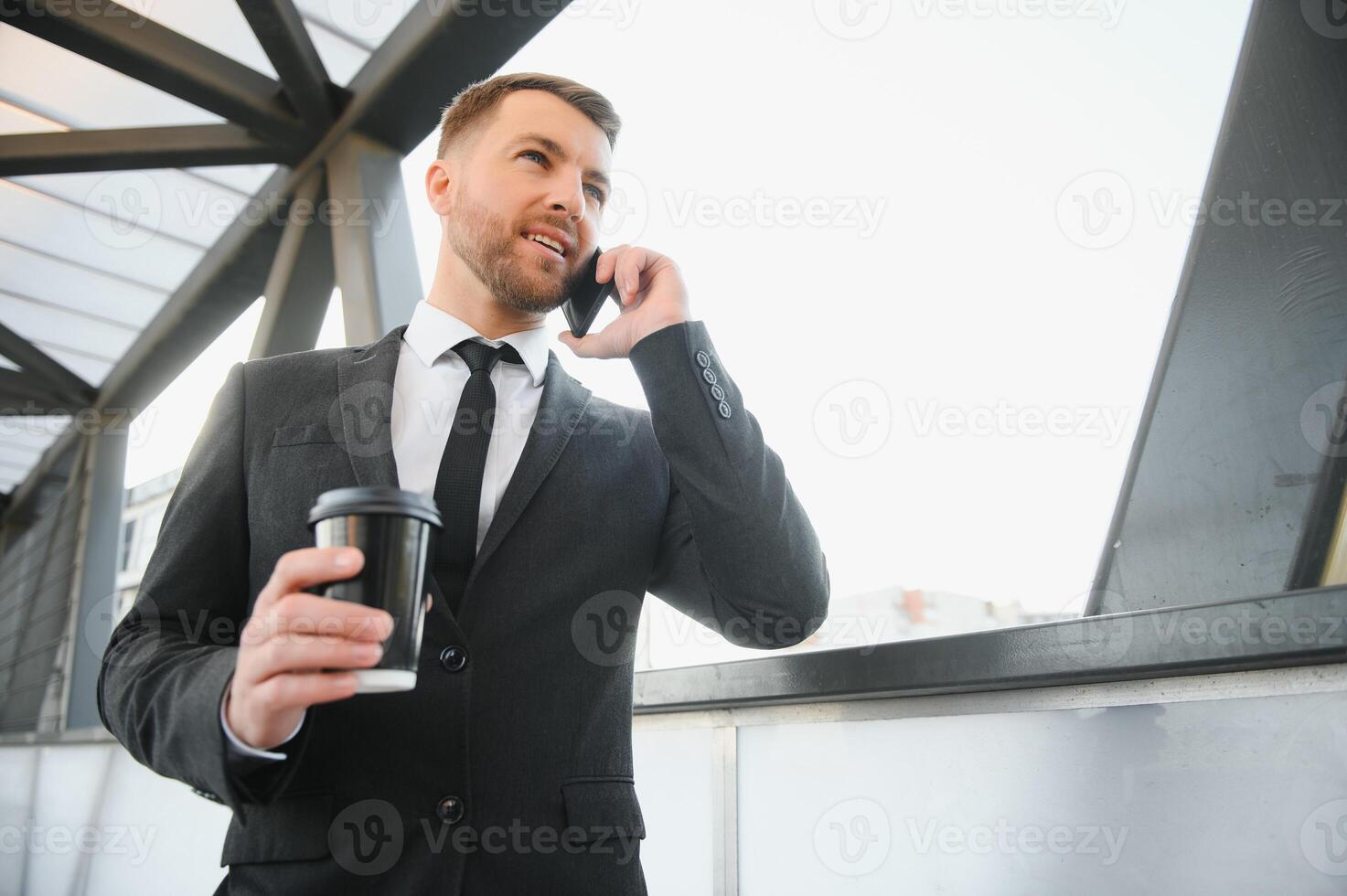 Bearded businessman in formal suit on break using mobile phone use smartphone. business man standing outside on modern urban city street background with coffee cup in downtown outdoors. copy space photo
