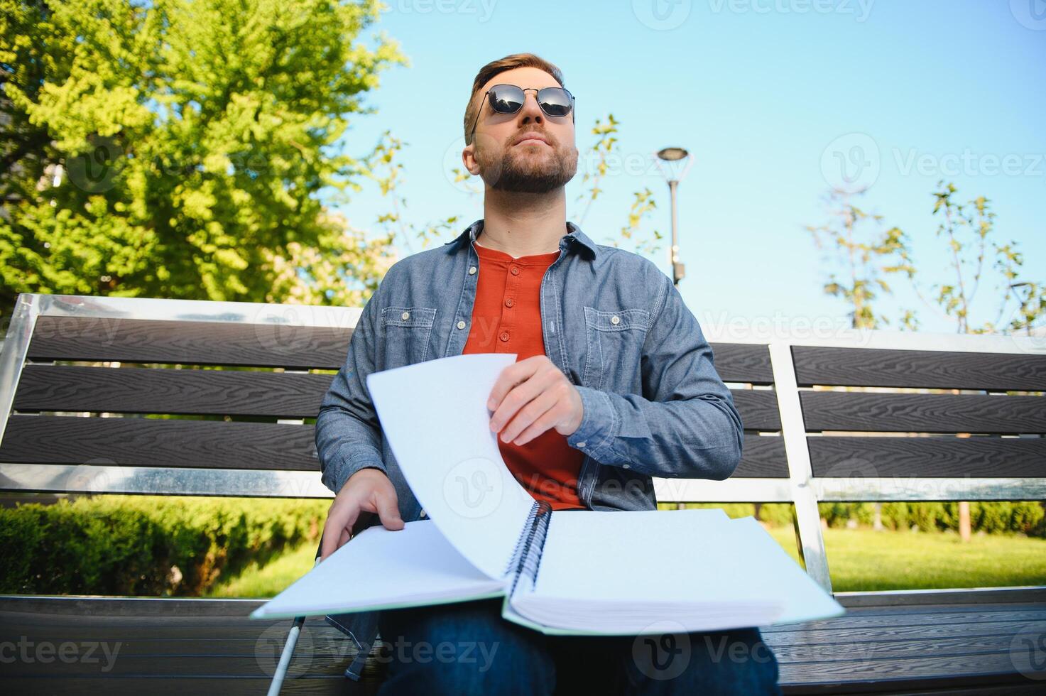 Blind man reading book on bench in park photo