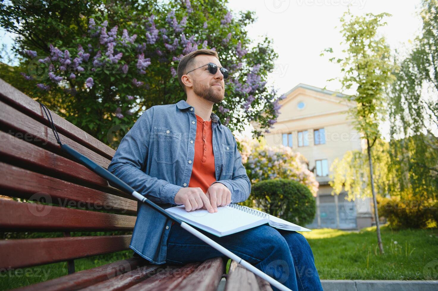 Blind man reading book on bench in park photo