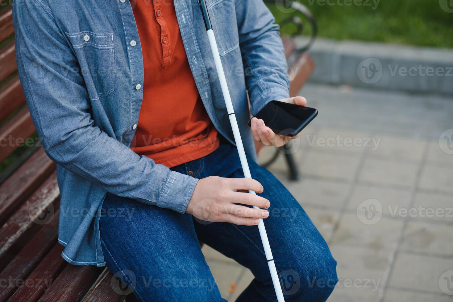 Young blinded man using phone and sending voice message photo