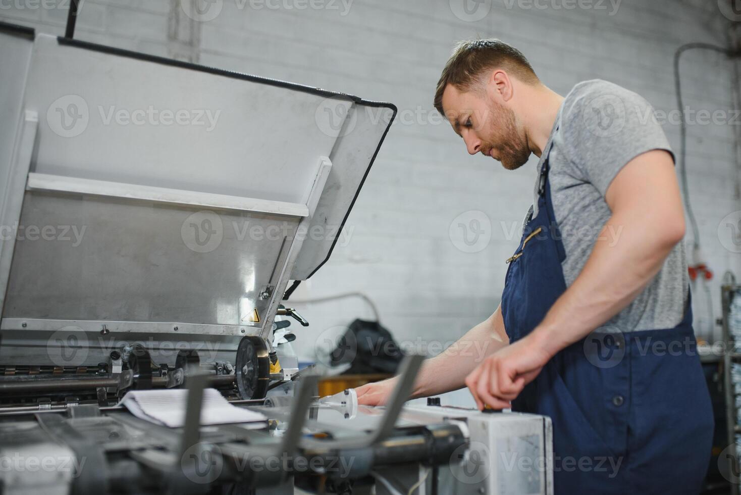 worker in protective clothing in factory using machine photo