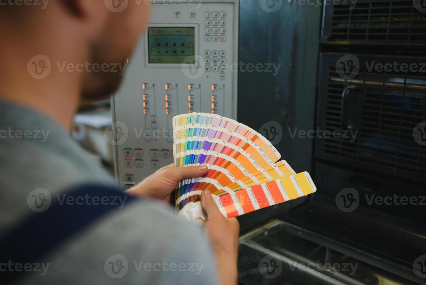Portrait of production line worker controlling manufacturing process of modern packaging industrial machine in printing factory photo
