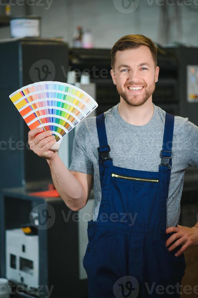 Portrait of worker at control room checking print quality at printing house. photo