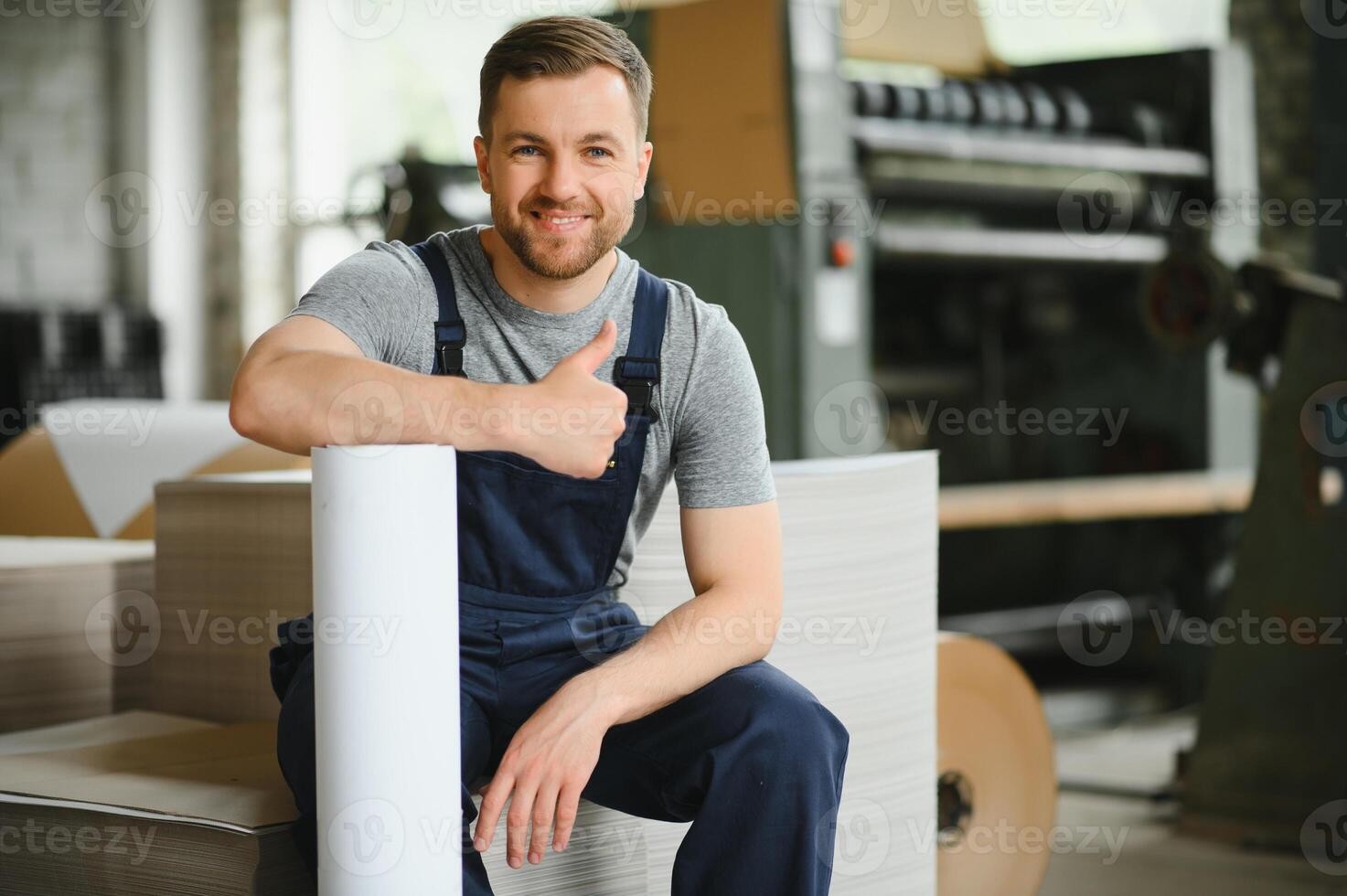 Smiling and happy employee. Industrial worker indoors in factory. Young technician with white hard hat. photo