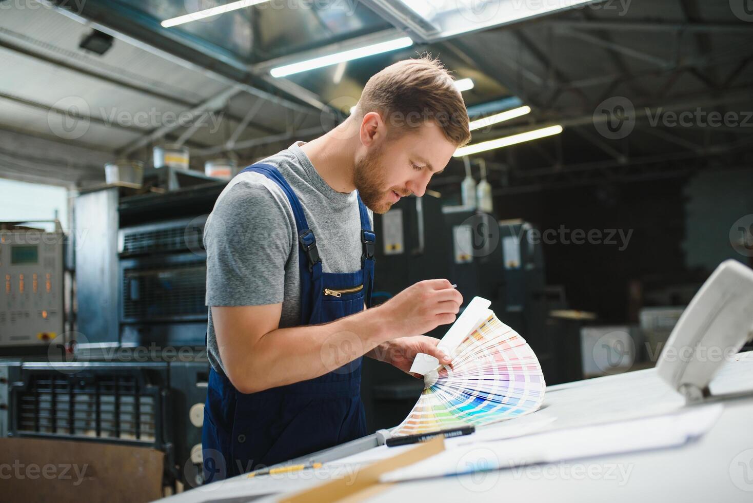 Man worker measuring printing color with spectrometer on the operating desk of the printing plant photo