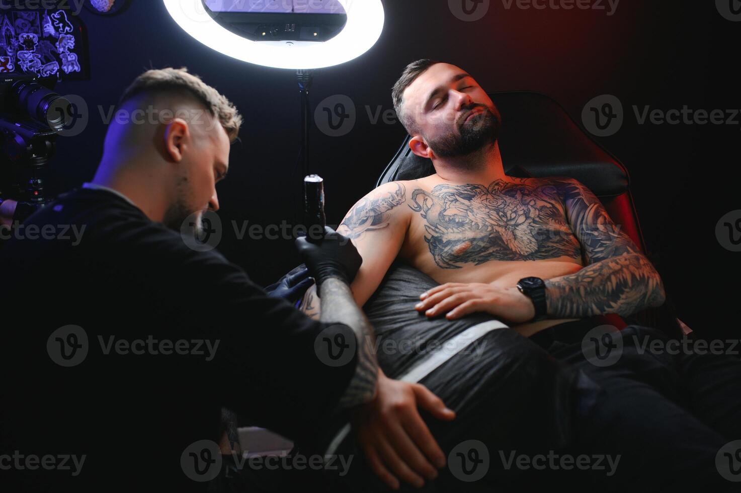 Portrait of a tattoo master showing a process of creation tattoo on a hand under the lamp light photo