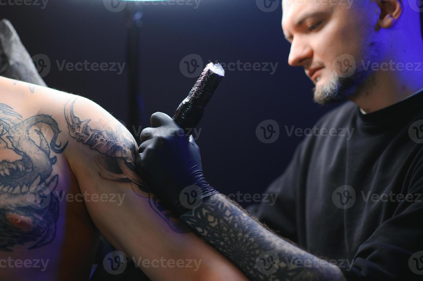 Tattoo artist hands wearing gloves and holding a tattoo machine photo