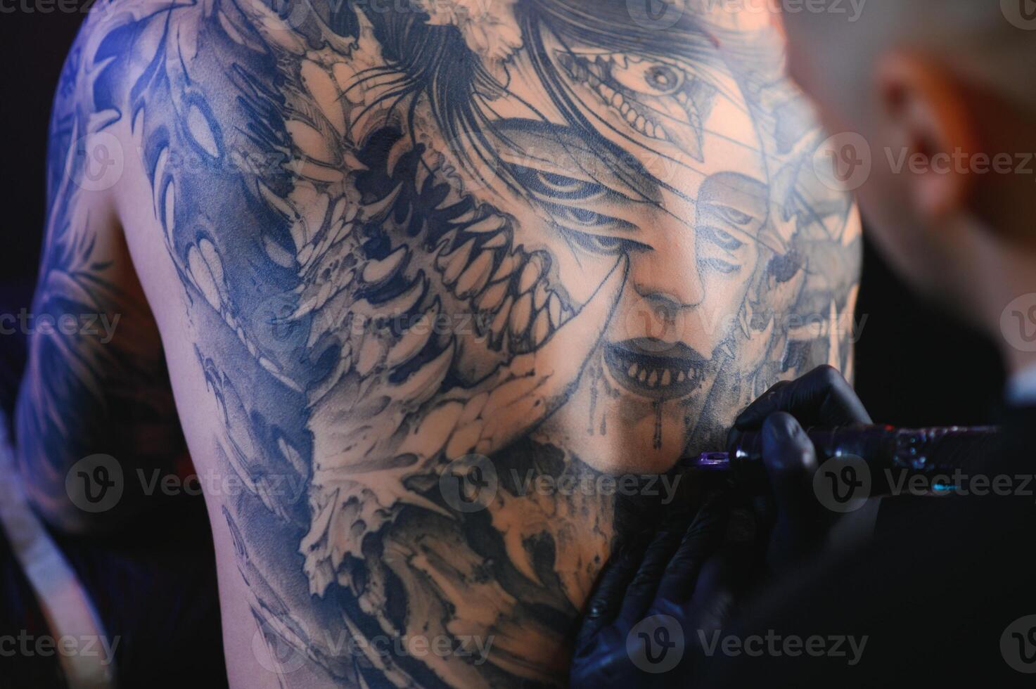 Shot of a tattoo artist hands forming perfect lines on man back with ink photo