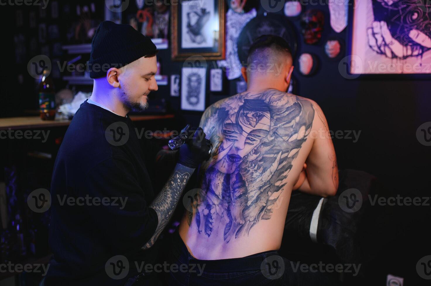 Tattooing. Man creating a picture on his back by a professional tattoo artist photo