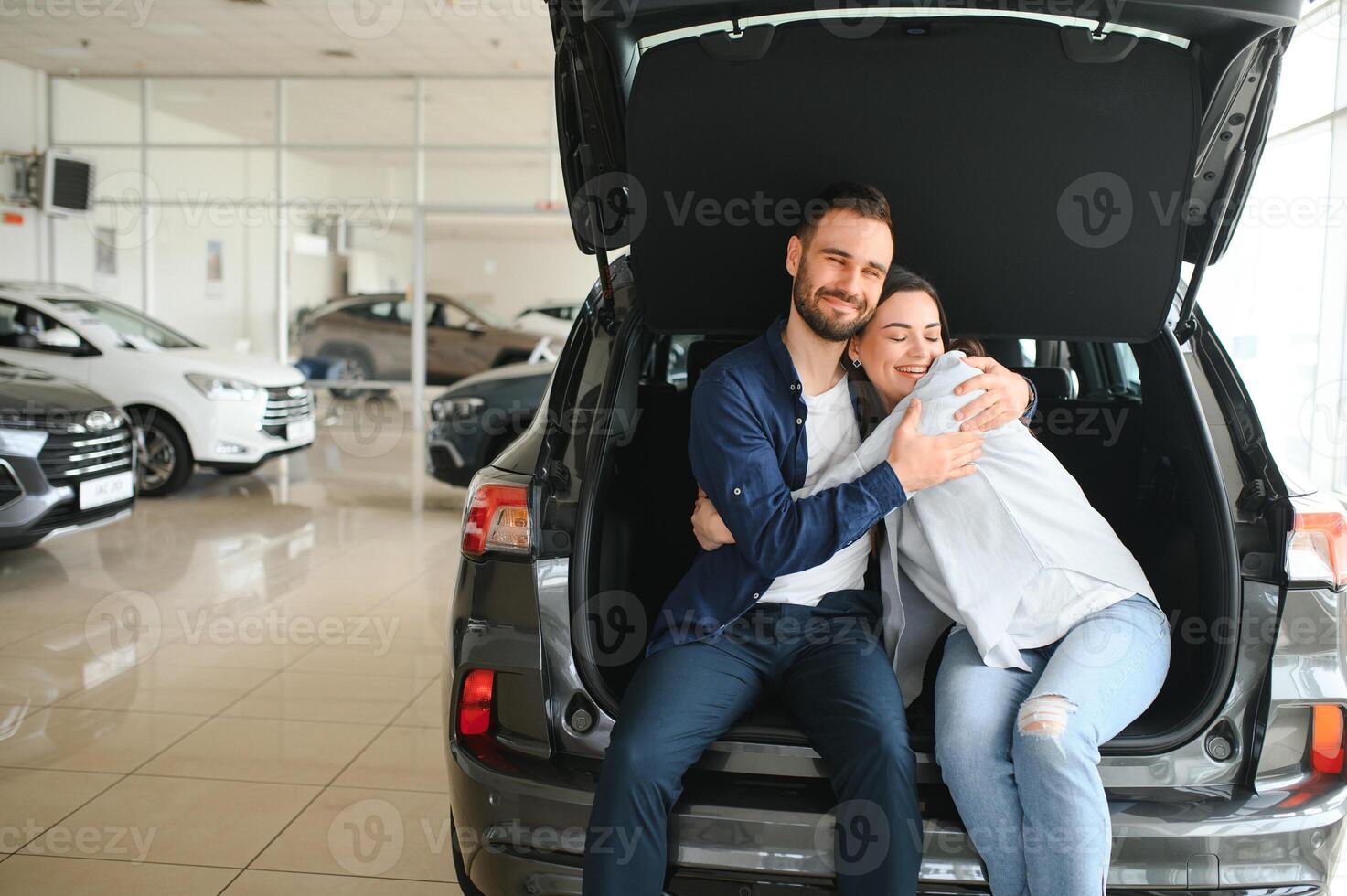 First big buy together. Portrait of a happy young couple hugging in a car salon photo