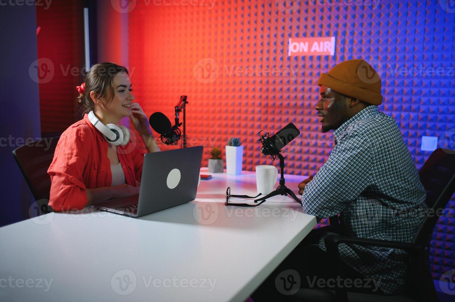 two radio hosts in headphones laughing while recording podcast in studio together photo