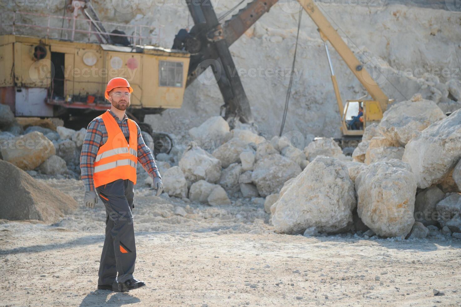 Worker in hardhat standing in stone quarry photo
