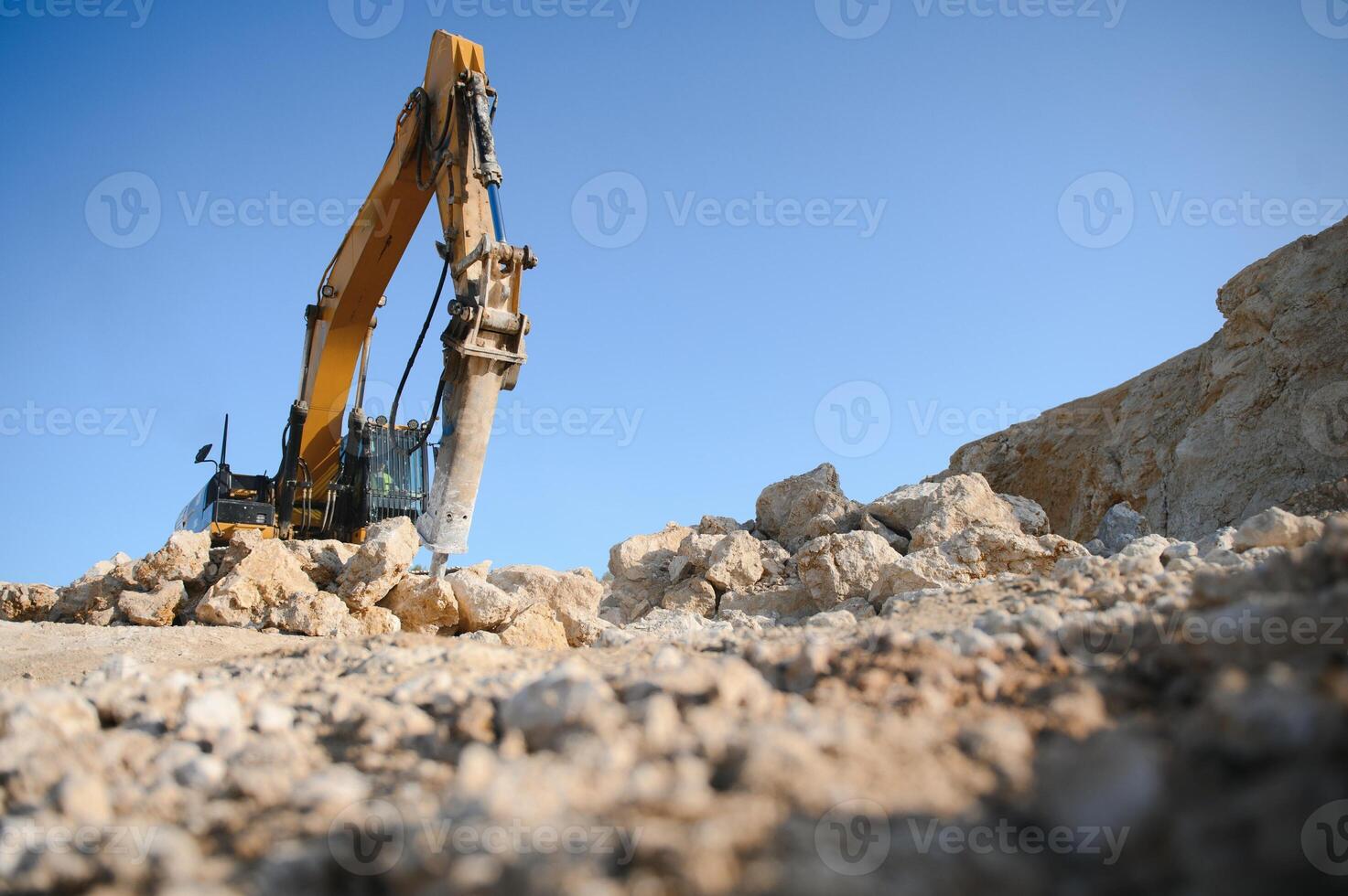 Hydraulic breaker hammer in a quarry for limestone mining with an excavator photo
