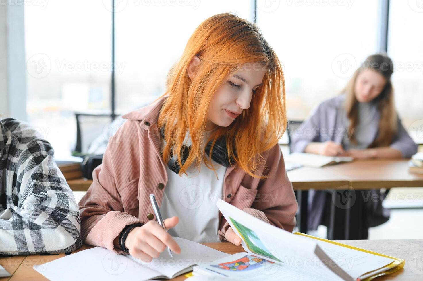 Testing. Closeup of young students sitting in a row and having test in their test-books photo