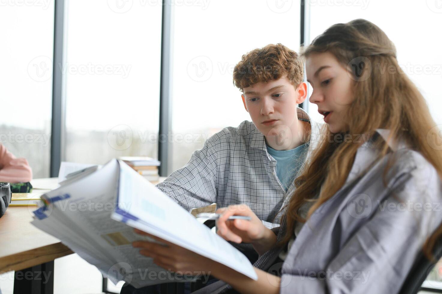 students sitting in a classroom, studying, discussing photo
