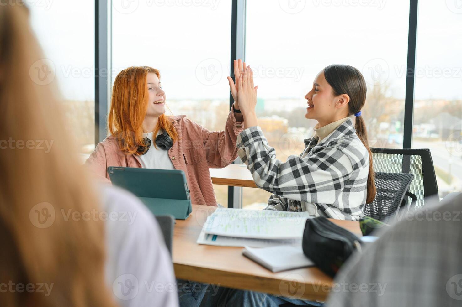 students sitting in a classroom, studying, discussing photo