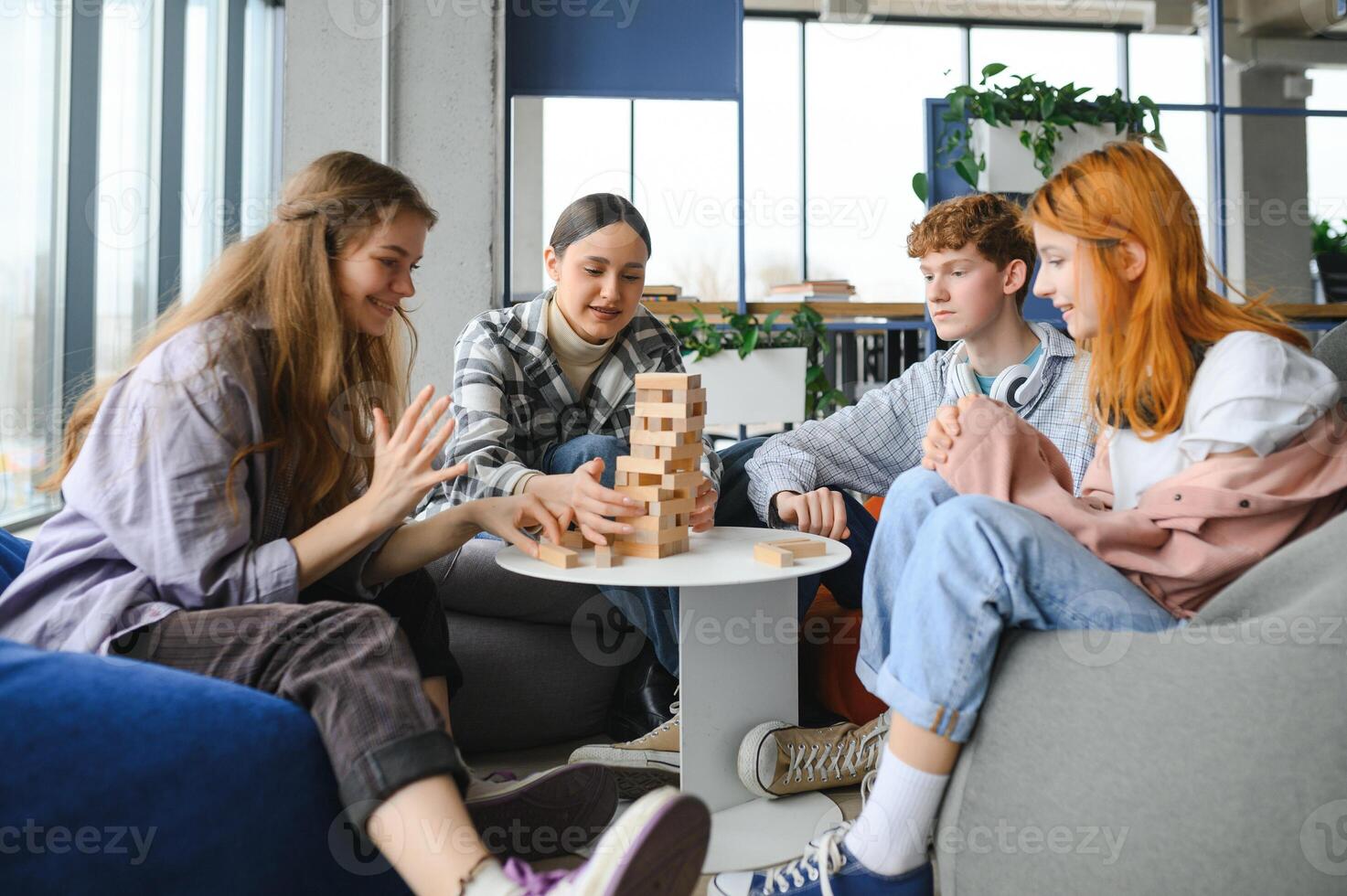 group of young friends playing board games together while sitting around table photo
