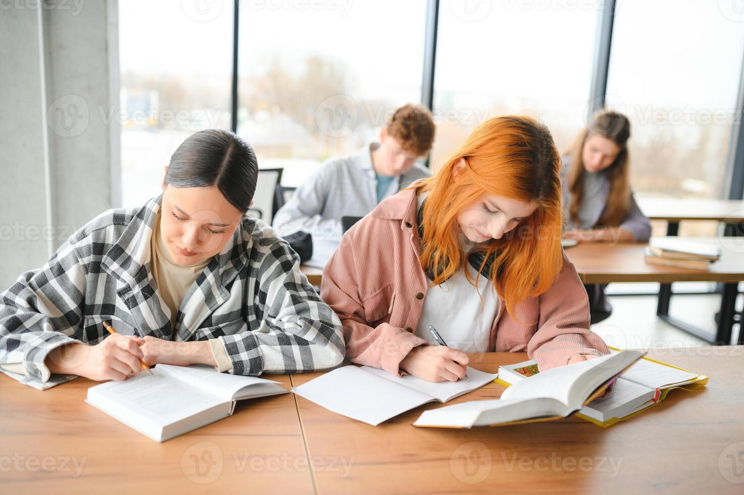 Testing. Closeup of young students sitting in a row and having test in their test-books photo