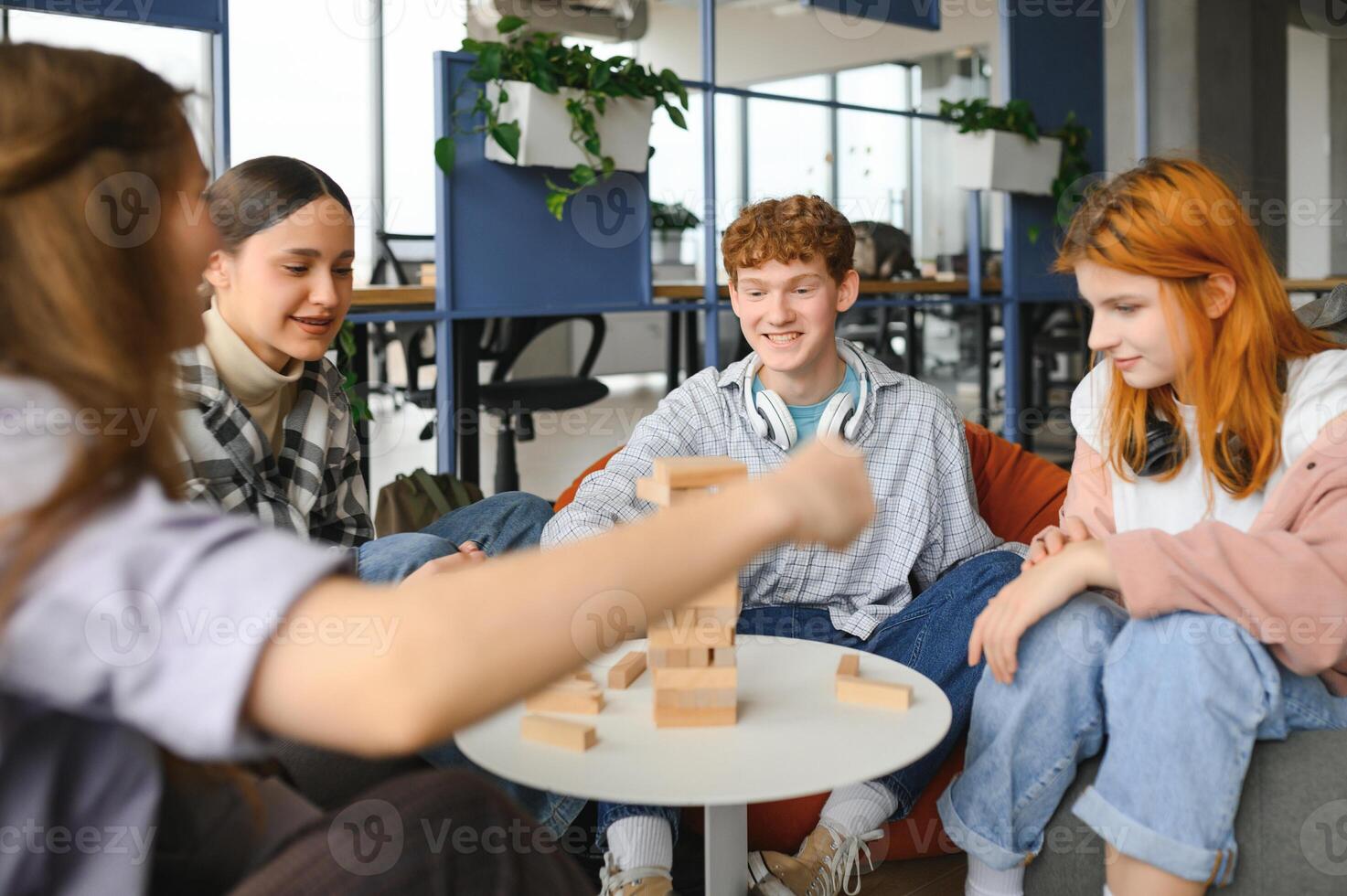 Group of creative friends sitting at wooden table. People having fun while playing board game photo