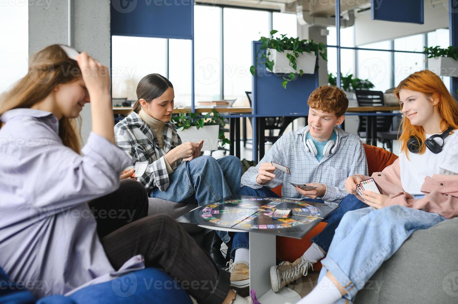 group of young friends playing board games together while sitting around table photo