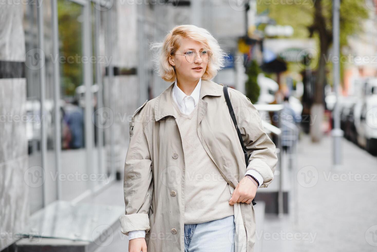 Young beautiful pretty girl walking along the street with handbag and cup of coffee. photo