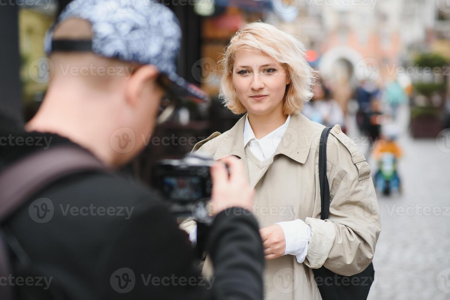 A girl makes a blog with a cameraman on the street. Young woman blogger, journalist filming with a professional camera and videographer. photo