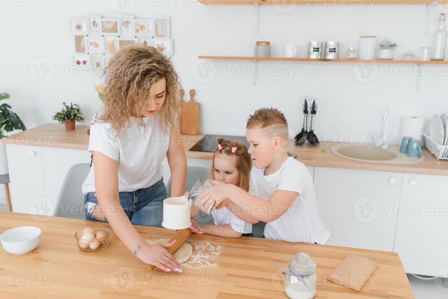 Family learning new recipe together. Happy mom and kids mixing ingredients for homemade cake, pie or cookie dough in the kitchen. photo