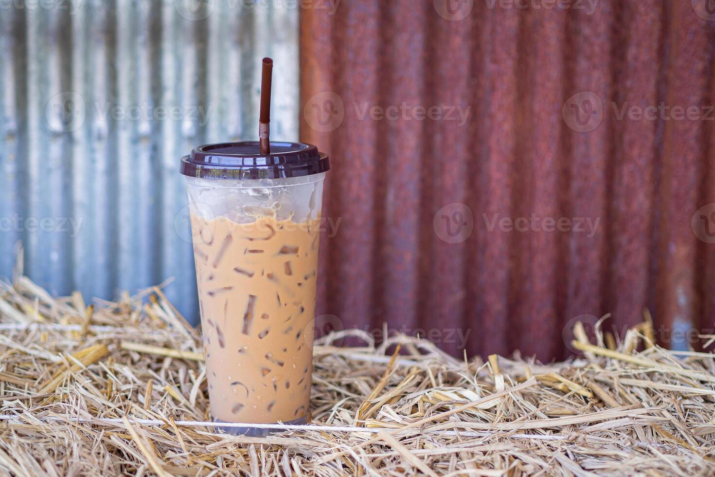 Iced coffee cup placed on a straw with a galvanized wall in the cafe shop. Space for text photo
