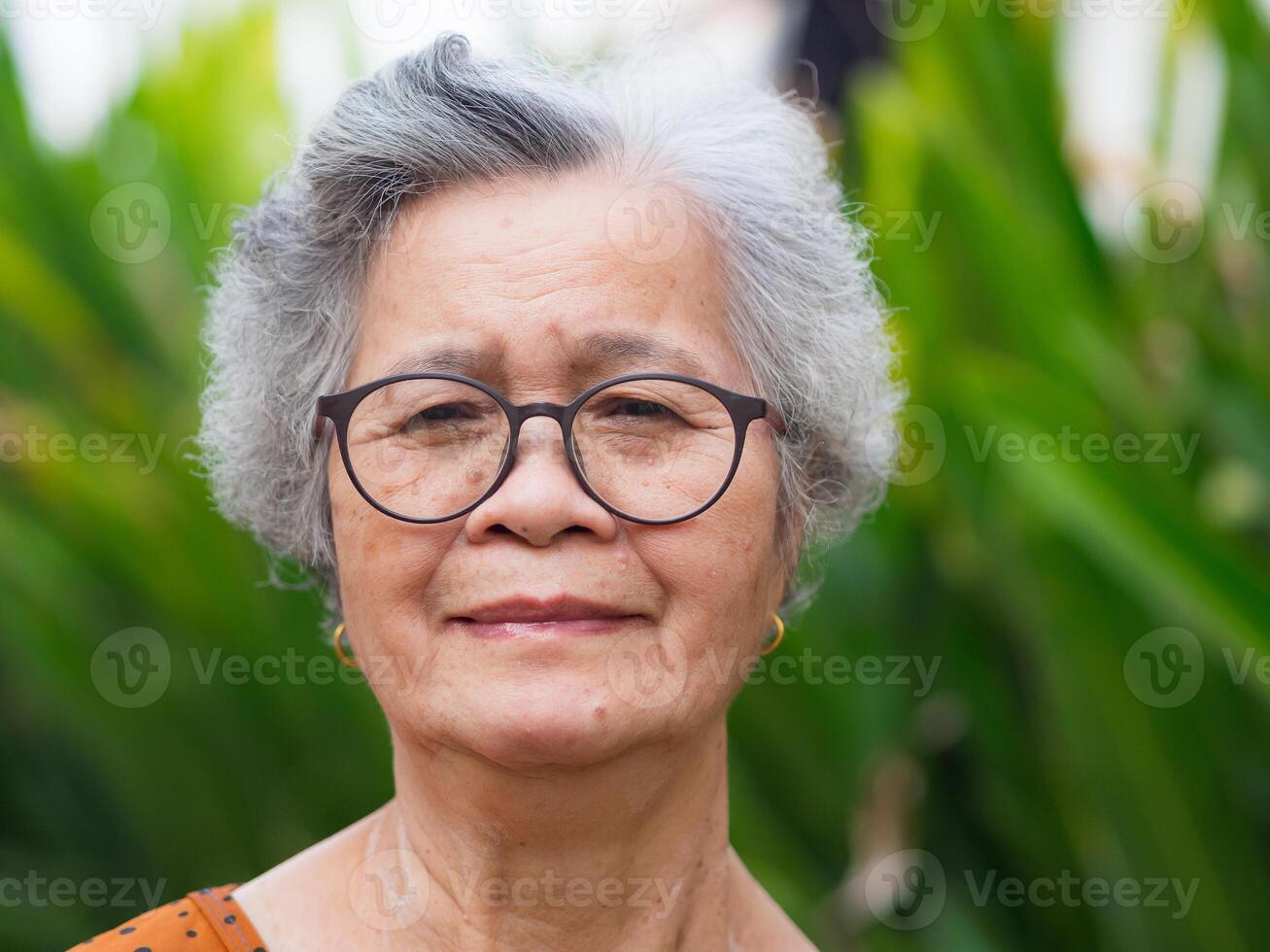 Portrait of an elderly woman looking at camera while standing in a garden photo